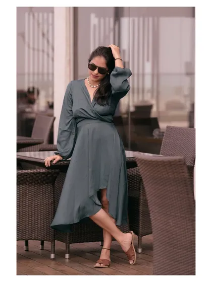 A lifestyle shot of a model in a grey wrap dress at an outdoor cafe. This image tells a story and shows the product in a real-world scenario.