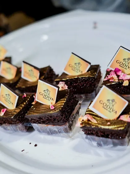 Elegant Godiva chocolate dessert bites, garnished with edible gold and rose petals for a touch of luxury.