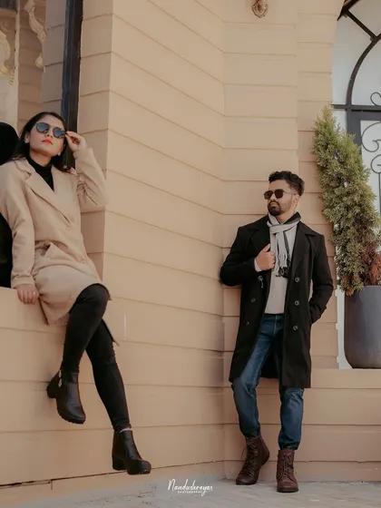 A cool, editorial-style portrait of a couple posing against a modern building, showcasing a more contemporary and fashionable pre-wedding style.
