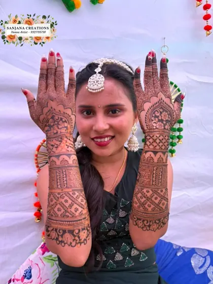 The bride proudly displaying both her hands, covered in beautiful, detailed mehndi for her special day.
