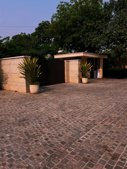 The simple, elegant entrance to the Sultanpur farmhouse, with a cobblestone driveway and two large planters framing the security post.