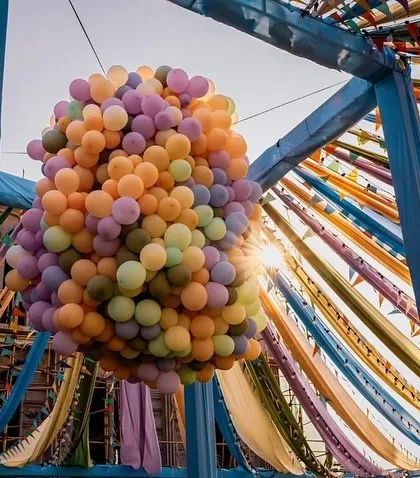 I love bringing vibrant energy to pre-wedding functions. For this carnival-themed event, I created a massive, multi-coloured balloon drop installation that hung from the ceiling, matching the colourful drapes and setting a fun, festive mood.