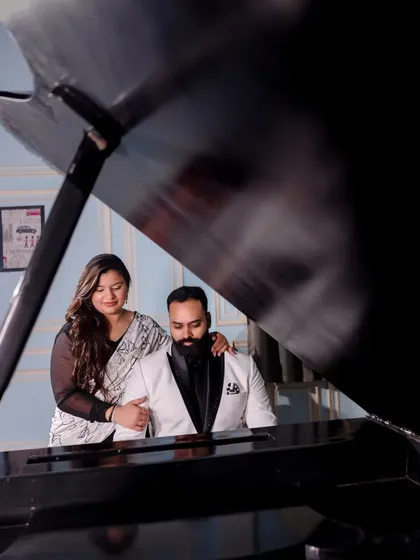 A beautifully framed shot of a couple at the grand piano. The composition uses the piano lid to create a unique and artistic perspective for this romantic portrait.
