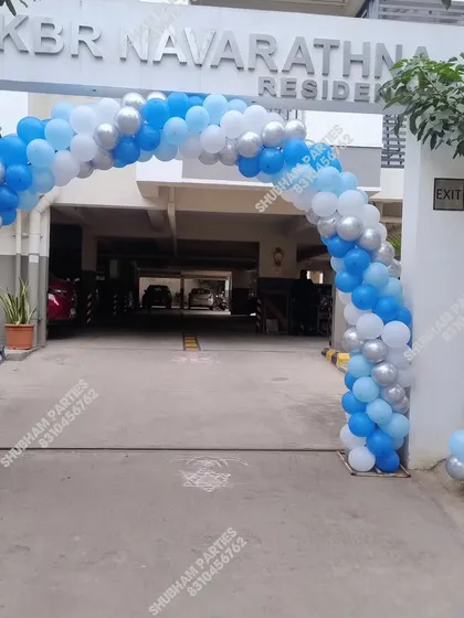A blue, white, and silver balloon arch at the entrance of an apartment building for an event.