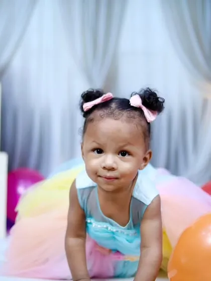 A curious one-year-old girl crawling towards the camera during her birthday session.