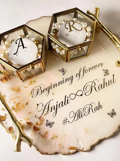 A top-down view of the classic white and gold tray, showing the full layout of the personalized text and ring boxes.