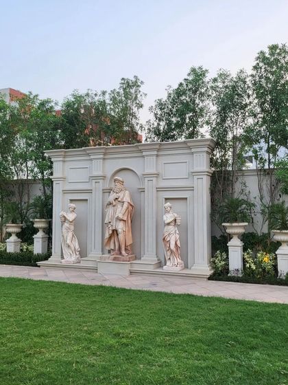 A magnificent feature wall with classical statues set in arched niches. This serves as a grand artistic statement, transforming a simple lawn into an outdoor gallery.