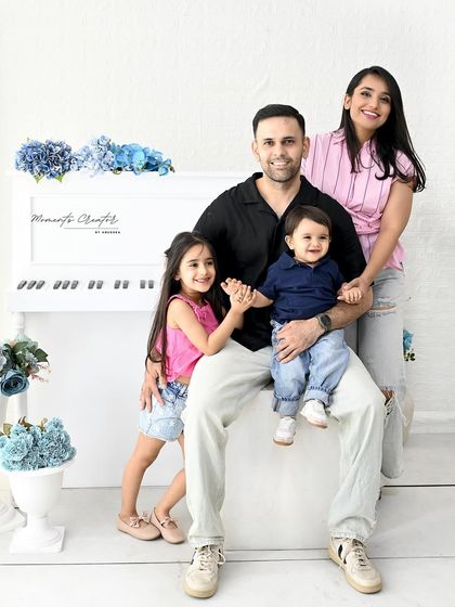 A relaxed and happy family photo. The father holds his son, who is reaching for his sister, creating a natural and candid family moment.
