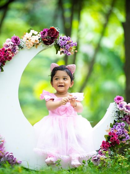 A magical moon prop set against a lush, green forest backdrop. This photo shows how we can bring creative studio elements outdoors for a truly unique look.