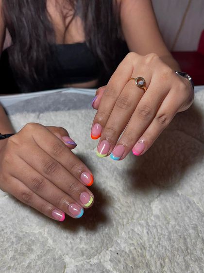A fun and colorful French manicure on short, rounded nails with a different neon color on each tip.