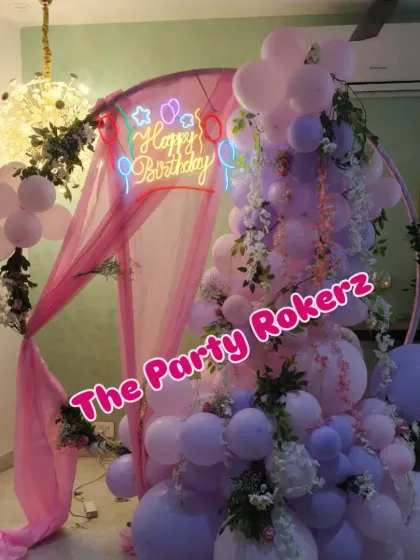 Another angle of the pink and purple room decoration, highlighting the cascading balloons and artificial flowers that create a soft, dreamy look.