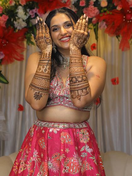 Raksha's joyful expression is infectious as she proudly displays her bridal mehendi.
