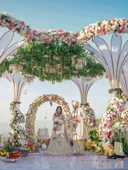 A breathtaking wide-angle view of a rooftop wedding mandap, showcasing the incredible floral decor and the couple at the center of it all.