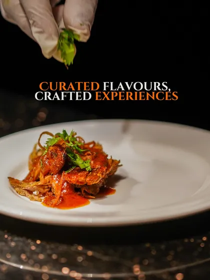 A chef adds a final squeeze of lime to a beautifully plated dish, representing our curated flavours.