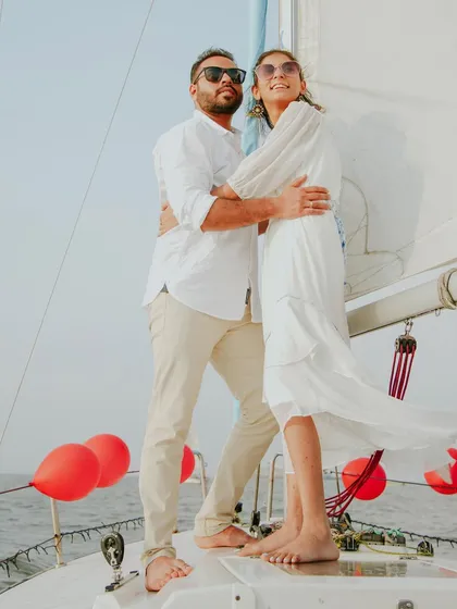 A stylish pre-wedding portrait on a sailboat. The wind in her dress and the open sea behind them create a sense of freedom and adventure, perfect for couples who want a unique and memorable shoot.