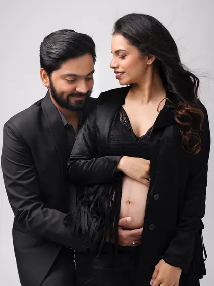 A tender moment between the parents-to-be. Her makeup is soft and natural, highlighting her pregnancy glow.