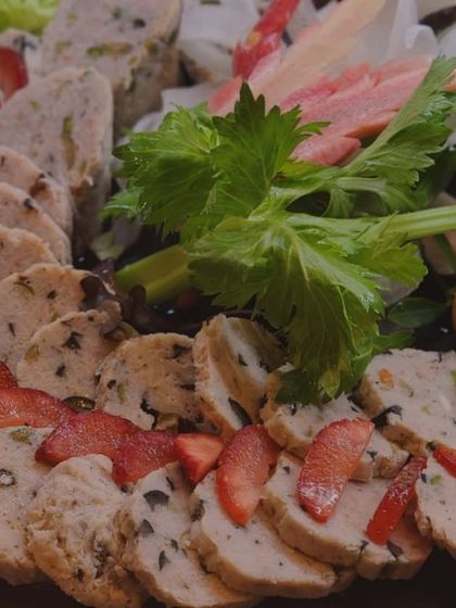 A close-up of expertly sliced charcuterie, garnished with fresh strawberries and celery leaves. This image emphasizes the quality and presentation of the cured meats I offer.