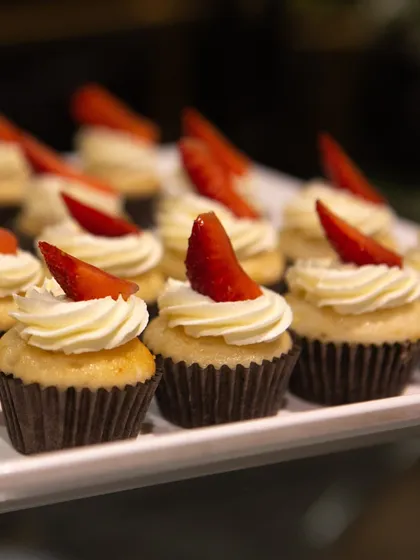 A close-up of our classic vanilla cupcakes with strawberry garnish. The simplicity of the presentation allows the quality of the ingredients to shine.