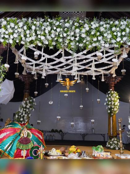 A traditional bell mantap designed for a Muhurtham ceremony. The structure is adorned with beautiful white flowers and intricate details, creating a sacred and stunning centerpiece for the wedding.