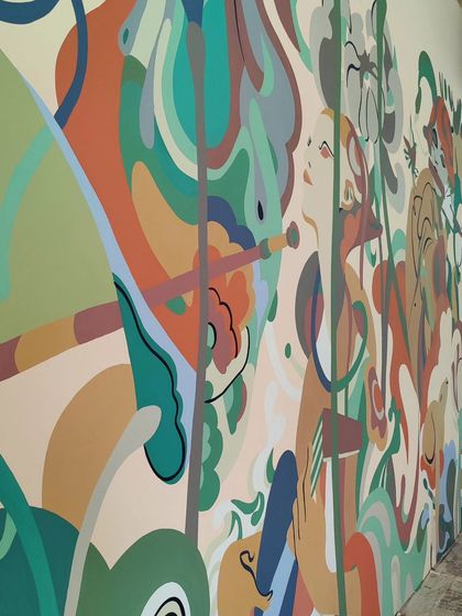 The mural unfolds with scenes of people and animals in a lush, dreamlike landscape, designed to transport diners to a different world.