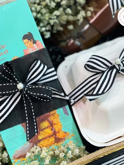 A close-up of the details in our groom-to-be hamper, showing the stylish black and white striped ribbons and pearl accents.
