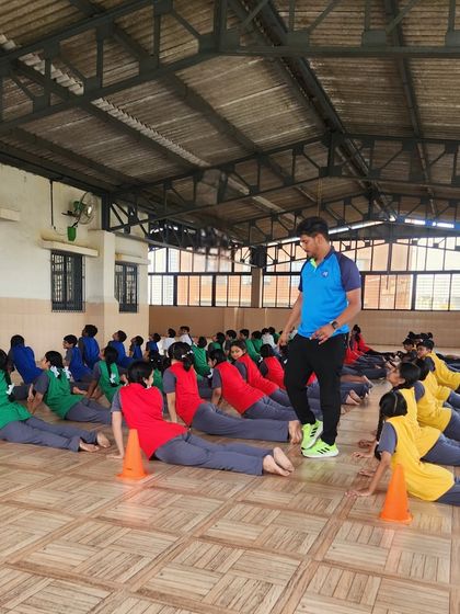 A coach guides students through the cobra pose. Our yoga sessions are structured to ensure proper form and to help students improve their flexibility and posture.