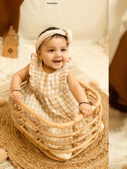 A joyful shot of a baby girl in a basket, looking up with a beautiful smile.