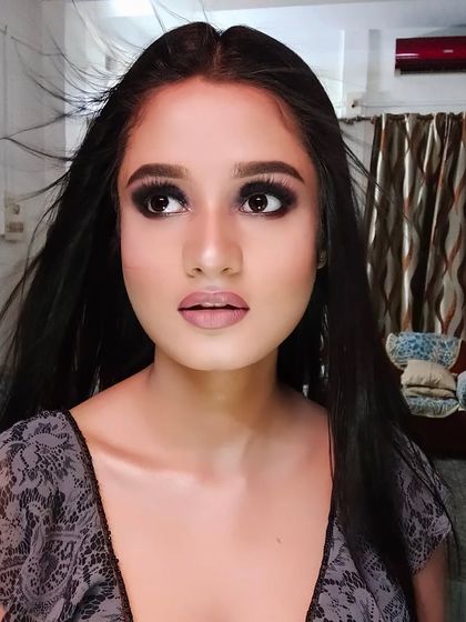 A dramatic, wind-swept photoshoot look. The focus is on the intense smokey eyes and flawless skin.