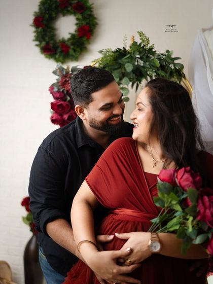 A close-up shot filled with laughter and love. This candid moment between the couple during their red-themed maternity shoot perfectly captures their happiness.