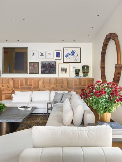 Natural light fills this casual lounge, highlighting the rich textures and art collection. The room is designed to be a buzzing hub for entertaining, connecting seamlessly to the main living room and the garden through large pocket doors.