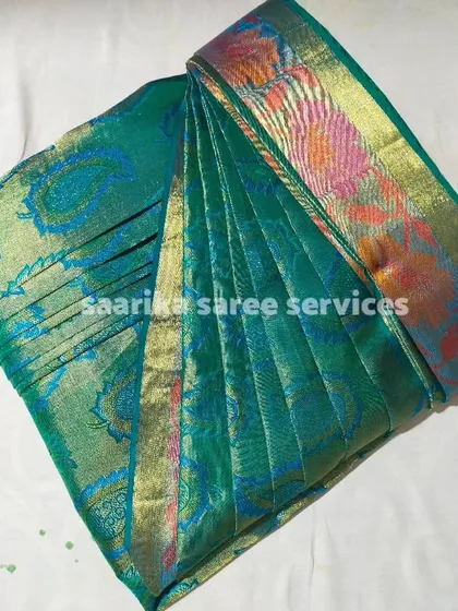 A teal green saree with a multi-colored border, showing the beautiful results of box folding.