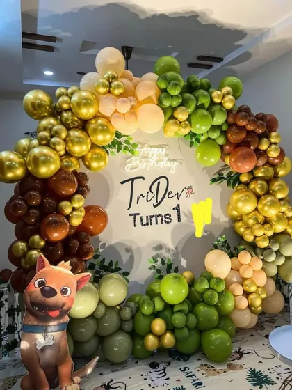 A Paw Patrol themed first birthday party with a jungle-colored balloon arch and a character cutout.