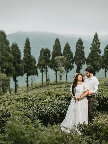 A beautiful portrait of a couple in a Darjeeling tea garden, with the bride wearing a lovely hat. The mountains in the background add to the scenic beauty of this destination pre-wedding shoot.