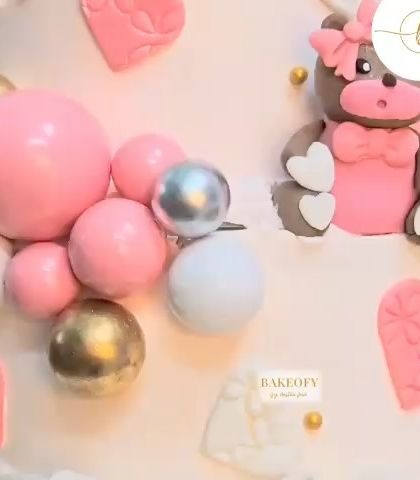 A close-up of another adorable fresh fruit cake, this one decorated with cute teddy bear toppers, colorful orbs, and a delicate fondant bow.