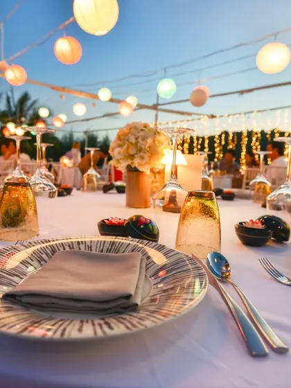 An evening event with tables set under a canopy of fairy lights and paper lanterns. This image captures the magical atmosphere we can help create for outdoor celebrations.