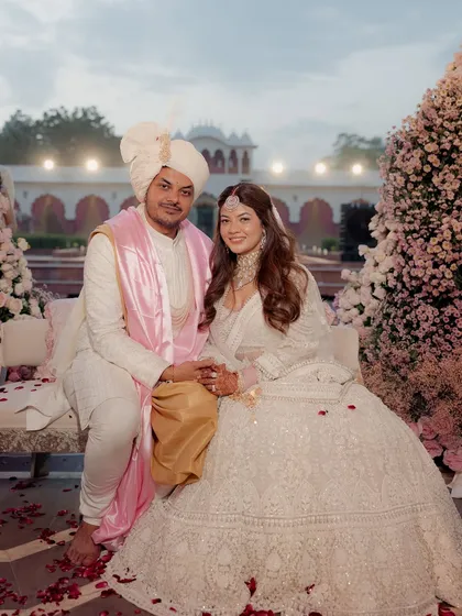 The couple seated amidst the sea of pink flowers. The soft textures and romantic colors of the decor create a perfect setting for their portraits.
