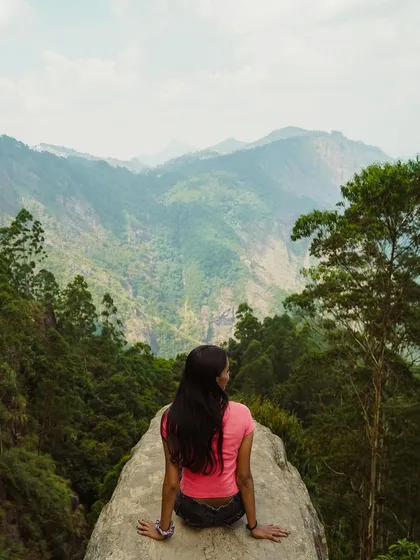 A woman sits on a rock overlooking the Vattakanal valley in Kodaikanal. This is the perfect spot for quiet contemplation and appreciating the beauty of the Princess of Hills.