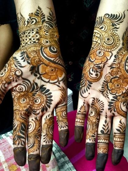 This Indo-Arabic design combines bold, dark floral work with delicate net patterns on the wrist. The contrast creates a very dynamic and eye-catching effect.