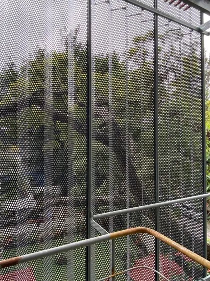 A view through the perforated metal screen we designed for a commercial building in Bangalore. The folded, layered skin acts as a veil, reducing glare and creating a dynamic play of light and shadow while offering a modern counterpoint to the surrounding greenery.