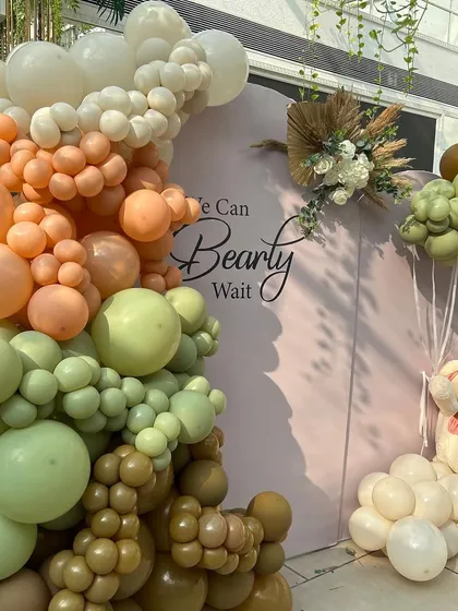 A detailed view of the ombre-style balloon garland, blending from white and peach tones into shades of olive and brown.