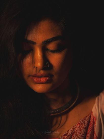 This low-key portrait uses shadows to create a dramatic effect. The makeup focuses on highlighting the skin's texture and bone structure for a warm, artistic shot.