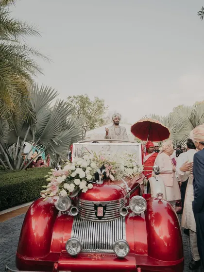 The groom's grand entry in a vintage red car, complete with a royal umbrella. I love planning these stylish and memorable Baraat moments.