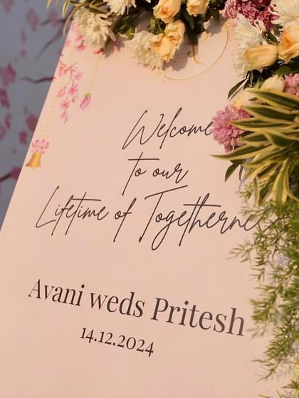 A beautiful welcome sign for Avani and Pritesh, with elegant calligraphy and a soft floral design, perfectly complemented by a lush flower arrangement.