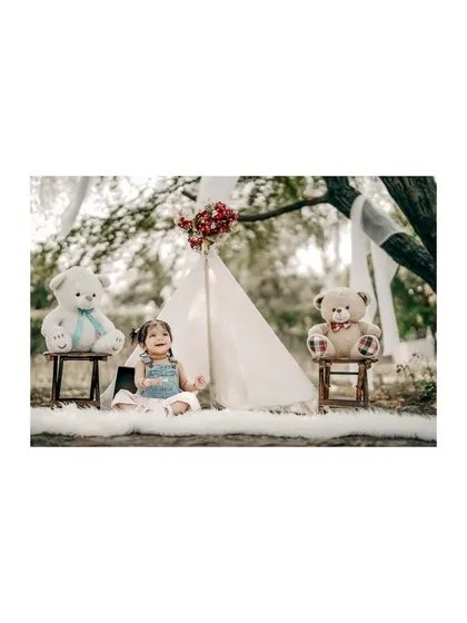 Looking up with a curious smile. This little girl is having a lovely time at her teddy bear picnic, surrounded by nature and her furry friends.