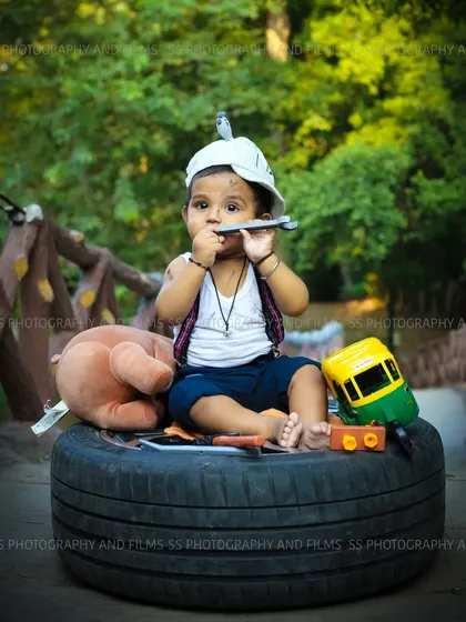 This creative "little mechanic" themed photoshoot for a toddler was set up outdoors. We used a variety of props like a tire, tools, and toys to build a fun and playful scene that captures his curious personality.