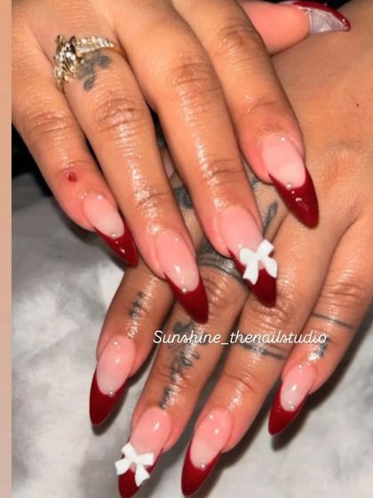 A trendy look for the festive season. These stiletto nails feature a deep red French tip with small, white 3D bows.