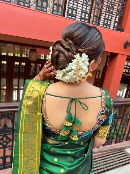 A side view of a classic bridal bun with a gajra. The way the hair is twisted and pinned creates a beautiful texture and shape.