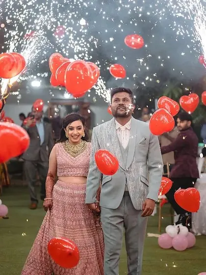 Your walk-in should be a celebration. Here, we created a path of joy with friends holding red heart balloons and cold sparklers, making the couple's entry feel vibrant and full of love.