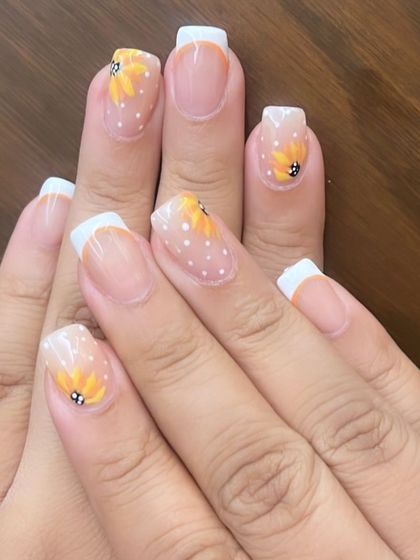 A cheerful French manicure with hand-painted sunflowers and white polka dots on the accent nails, bringing a touch of spring to your look.
