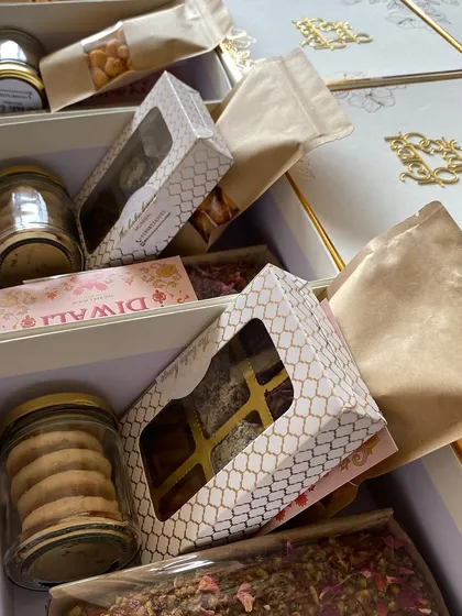 Assembling a large Diwali hamper with a variety of cookies, cakes, and savory snacks.